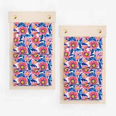 Two fabric swatches with a colorful floral pattern on wooden boards.