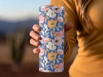 Woman holding a floral patterned tumbler with pink, white, and yellow flowers.