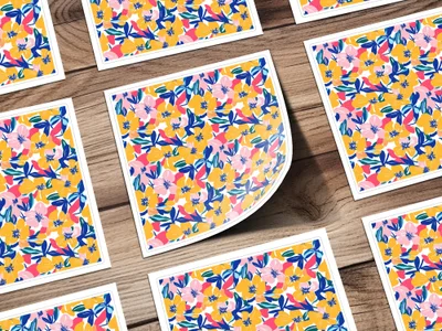 Several square cards with a floral pattern of pink, blue, and yellow flowers on a wooden surface.