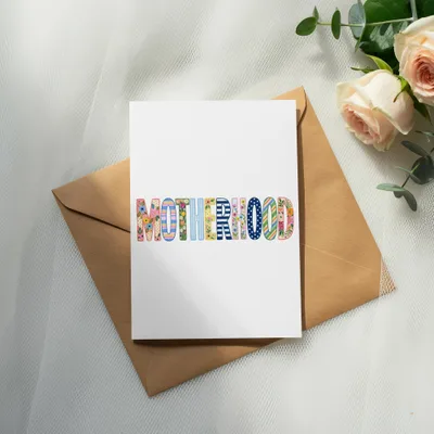 Card with "MOTHERHOOD" in colorful, patterned letters on envelope.