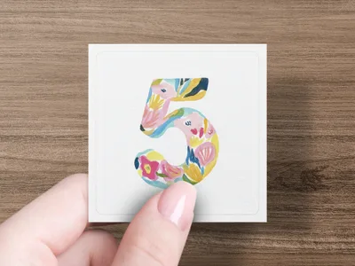 Hand holding a square card with a colorful floral number 5 design.