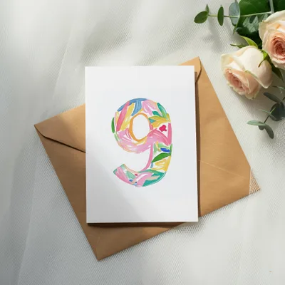 White card with "9" in colorful floral watercolor design on envelope.