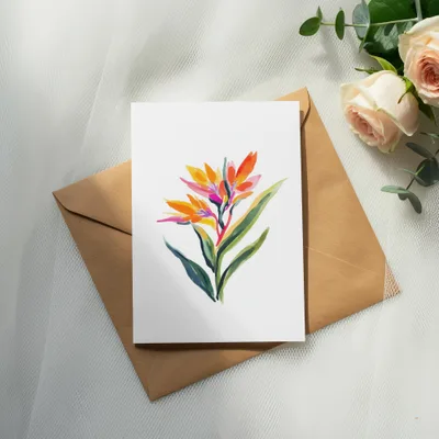Watercolor illustration of a Bird of Paradise flower on a card, resting on an envelope.
