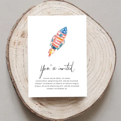 Watercolor rocket invitation on wood slice, reads "You're invited".