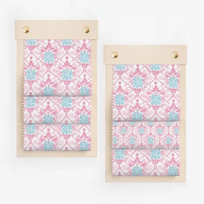 Two fabric swatches with pink and blue floral pattern on wooden boards.