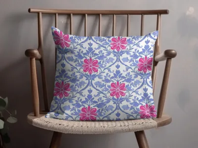 Throw pillow with a blue floral pattern on a wooden chair.