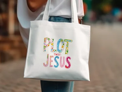 White tote bag with "Plot Twist: Jesus" in colorful floral lettering.