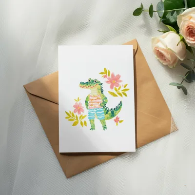 Card with cartoon alligator wearing striped shorts, surrounded by flowers.