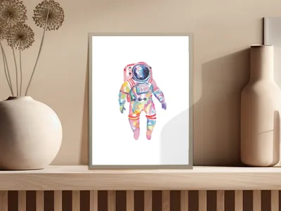 Watercolor astronaut illustration in a framed picture on a shelf.