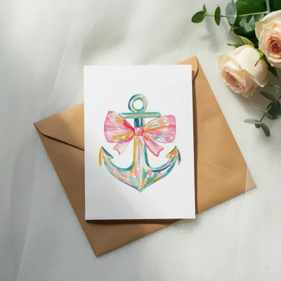 Watercolor anchor with pink bow on white card within a brown envelope.