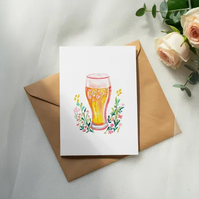 Watercolor illustration of a beer glass surrounded by colorful flowers on a card.