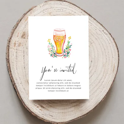 Invitation card with "You're invited" and floral design, on a wooden slice.