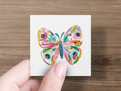 Colorful butterfly illustration on a white card held by a hand.