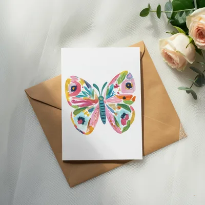 Watercolor butterfly card on a brown envelope with roses and eucalyptus.