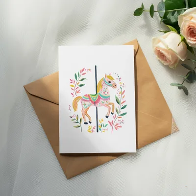 Card with carousel horse illustration and floral border on brown envelope.