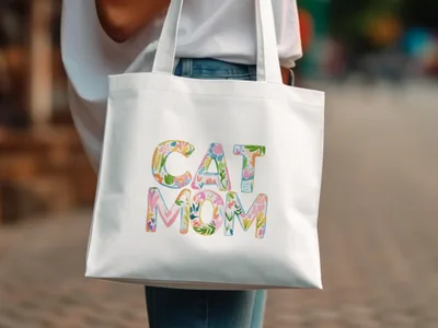 White tote bag with colorful floral "CAT MOM" text.