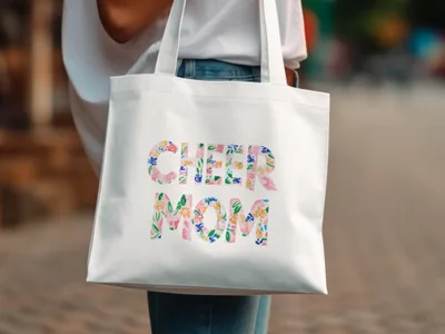 White tote bag with "CHEER MOM" in colorful floral lettering.