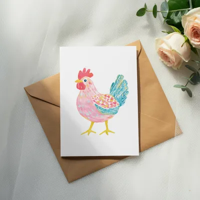 Watercolor illustration of a pink and blue chicken on a white card atop a brown envelope.