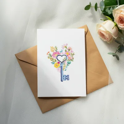 Card with heart-shaped floral design and vintage key, on brown envelope.