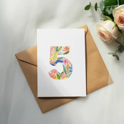 Card with colorful floral number 5 on brown envelope, with roses and eucalyptus.