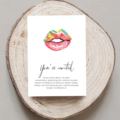 Card with "You're invited" and lips illustration, on wood slice.