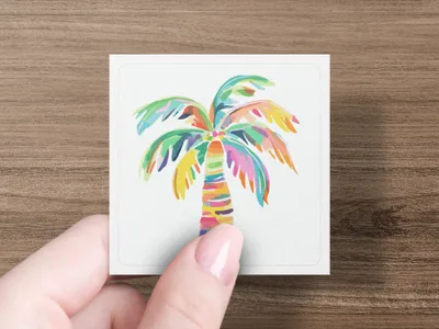 Colorful abstract palm tree illustration on a white card held by a hand.