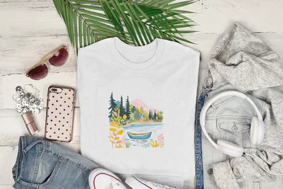 White t-shirt with nature scene of lake, trees, and mountains.