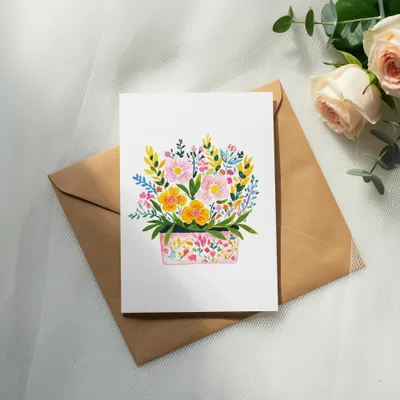 Watercolor floral arrangement on a white card atop a kraft envelope with roses.