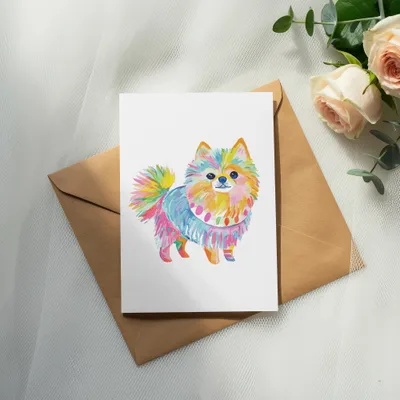 Watercolor illustration of a colorful Pomeranian dog on a card.