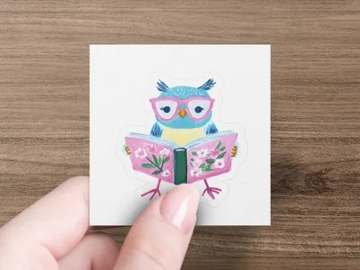 Blue owl wearing glasses reads a book with pink flowers.