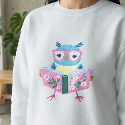 White sweatshirt with a cartoon owl wearing pink glasses reading a book.