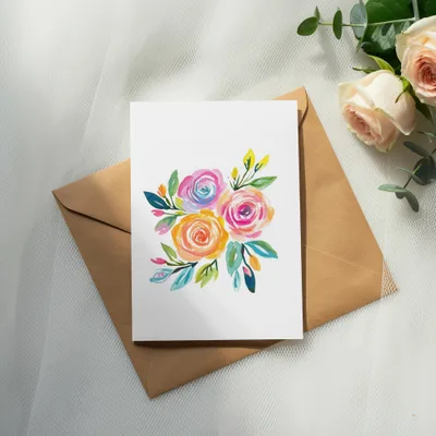 Watercolor floral bouquet painting on a white card atop a brown envelope.