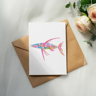 Colorful fish illustration on white card atop brown envelope with roses.