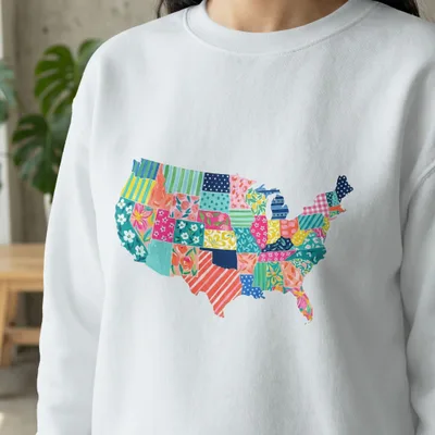 White sweatshirt with a colorful patchwork quilt map of the United States.