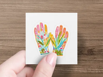 Decorative gardening gloves with floral patterns held by a hand.