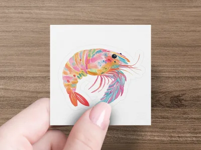 Colorful watercolor shrimp sticker on white paper held by a hand.