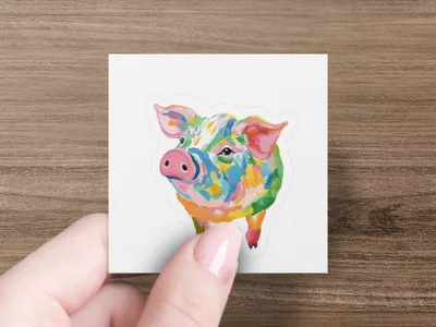 Colorful abstract pig illustration on a white square sticker held by a hand.