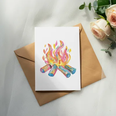 Watercolor campfire illustration on a card atop a brown envelope with roses.