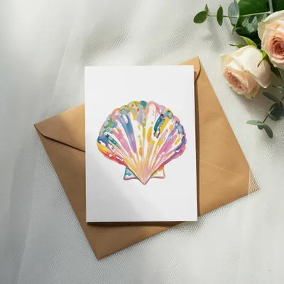 Colorful watercolor seashell illustration on cardstock, resting on a brown envelope.