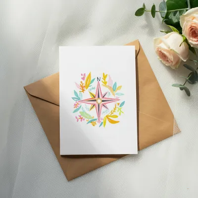 Card with floral compass design on brown envelope, with roses and eucalyptus.