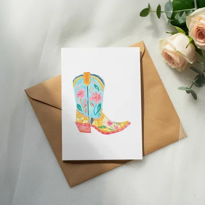 Colorful cowboy boot illustration on white card over brown envelope with roses.