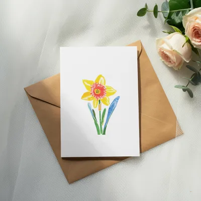 Watercolor daffodil illustration on a white card, atop a brown envelope.