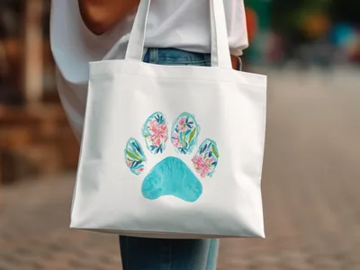 White tote bag with a teal paw print filled with colorful floral watercolor designs.