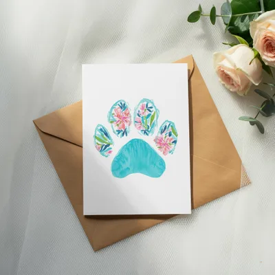 Watercolor paw print card with floral accents on a brown envelope.
