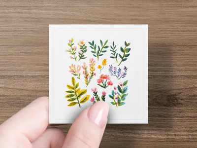 Watercolor floral sprigs and blooms on a white card held by a hand.