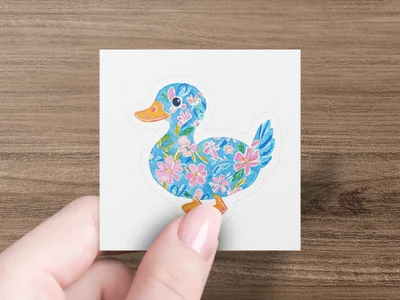 Blue duck sticker with pink floral pattern held by fingers.