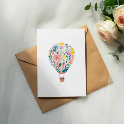 White card with floral hot air balloon design on brown envelope.