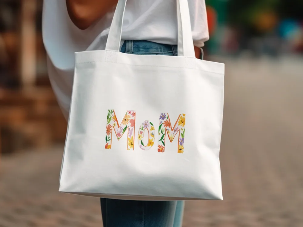 White tote bag with floral "Mom" lettering.