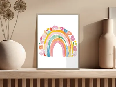 Watercolor rainbow with floral accents framed on a shelf.