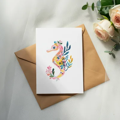 Watercolor seahorse illustration on a card with roses and eucalyptus.